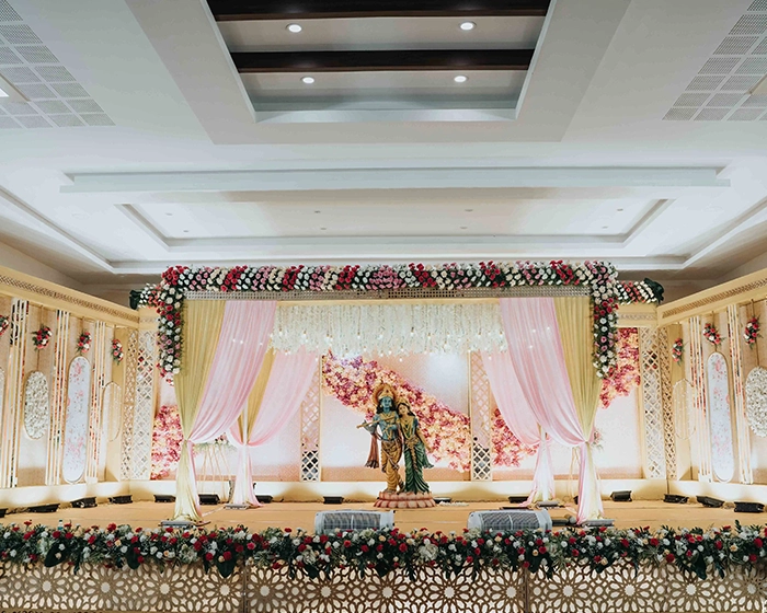 Wedding stage decoration featuring Krishna Radha statue and elegant floral styling